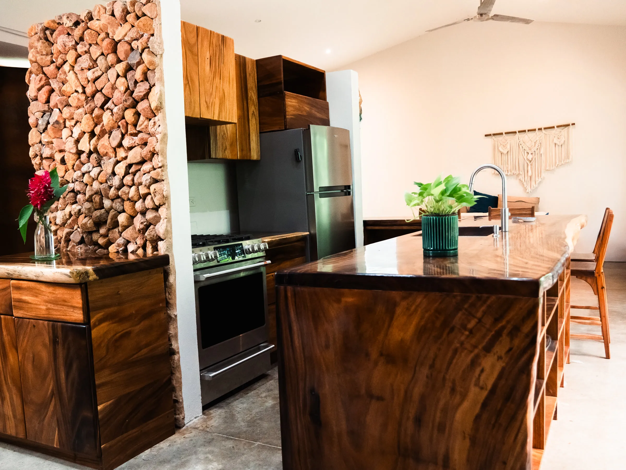 Cocina a medida en Guanacaste macizo con isla, muebles altos y pared de piedra